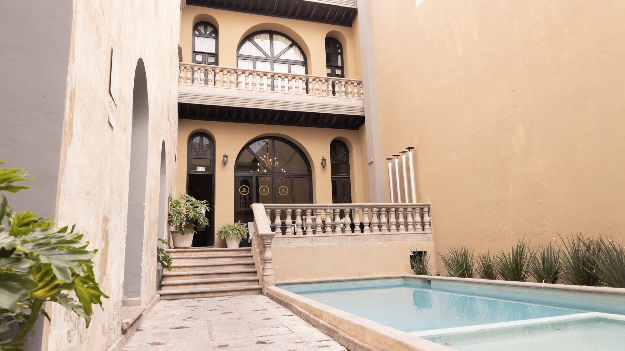 La alberca del hotel de día, con la escalinata de cantera y la fachada interior al fondo