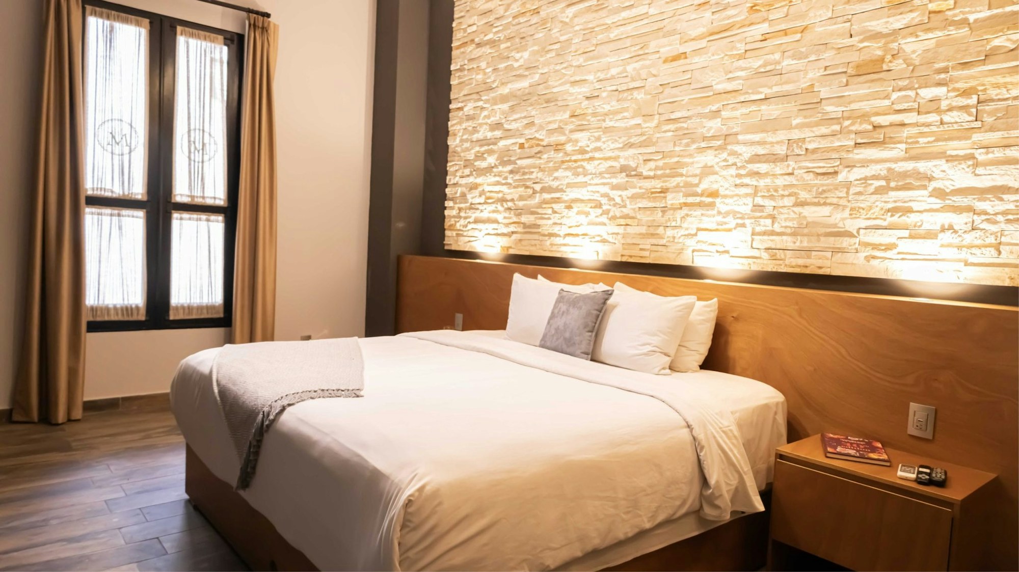 La habitación Clásica con su cama matrimonial y el muro de piedra iluminado