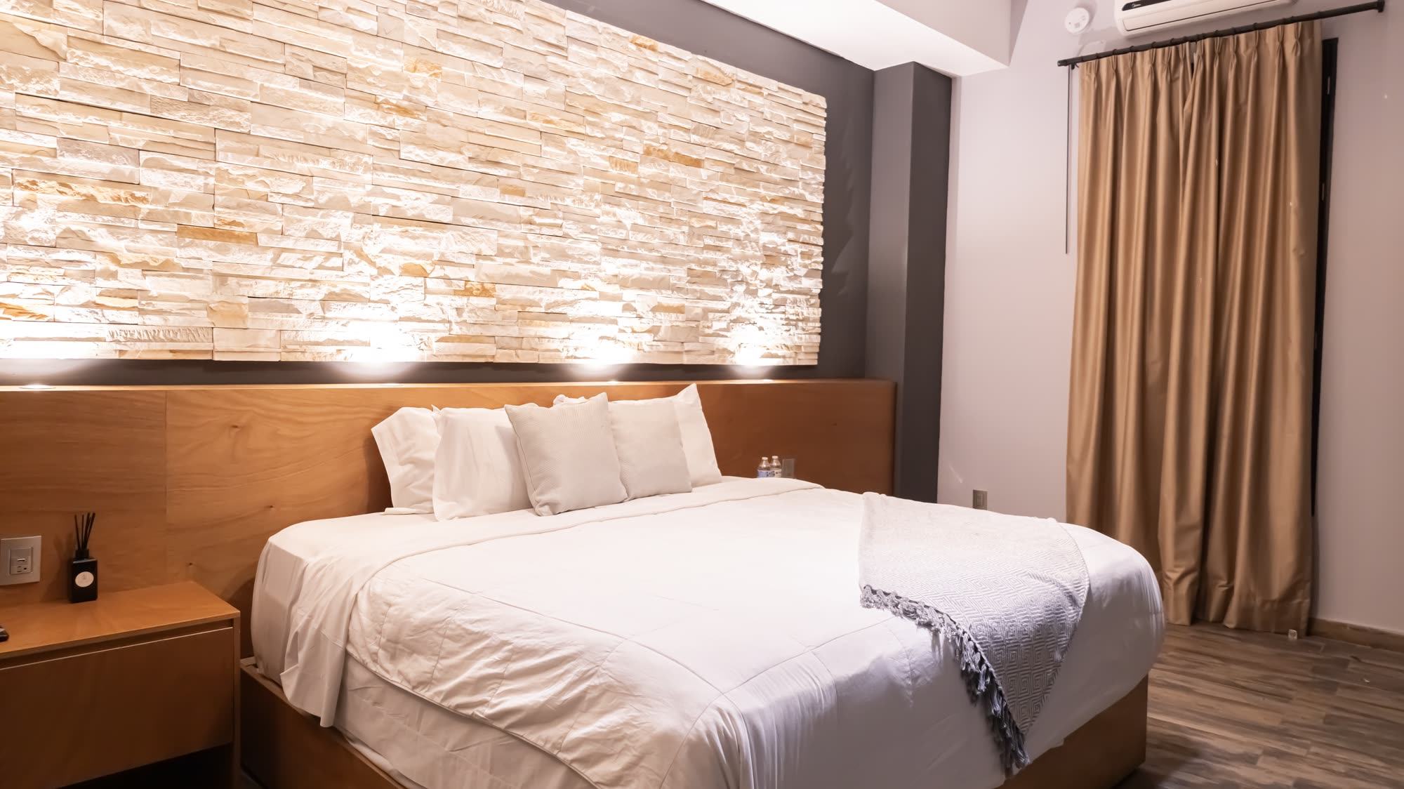 La cama de la habitación Deluxe 202 con su muro de piedra iluminado