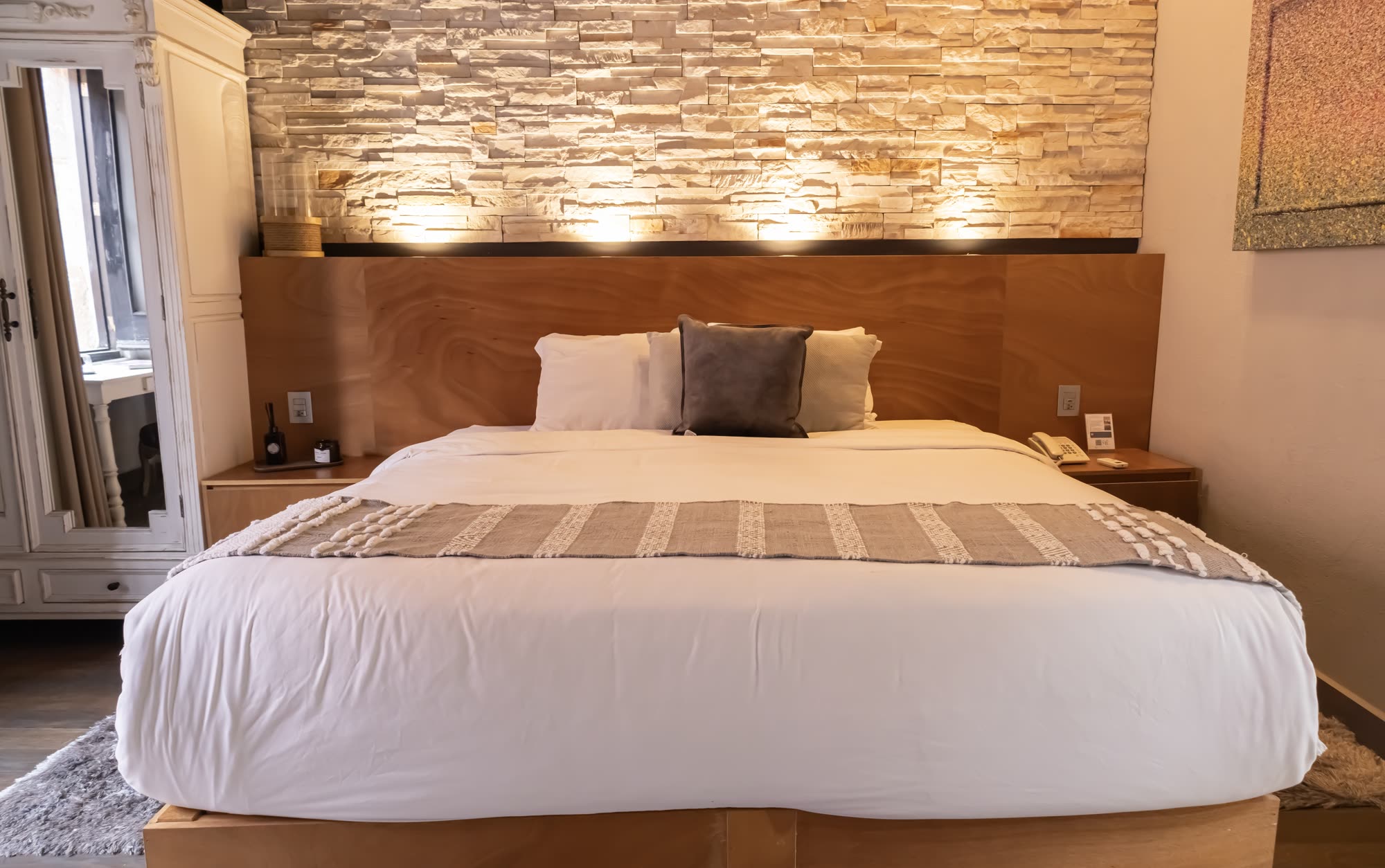 La cama de la Jr Suite 215 frente al muro de piedra iluminado