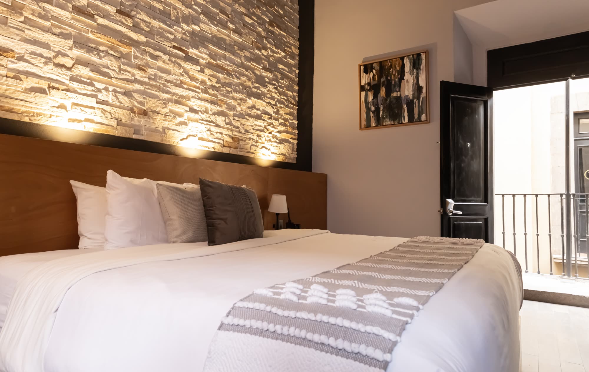 La cama de la Jr Suite 216 junto a la puerta del balcón