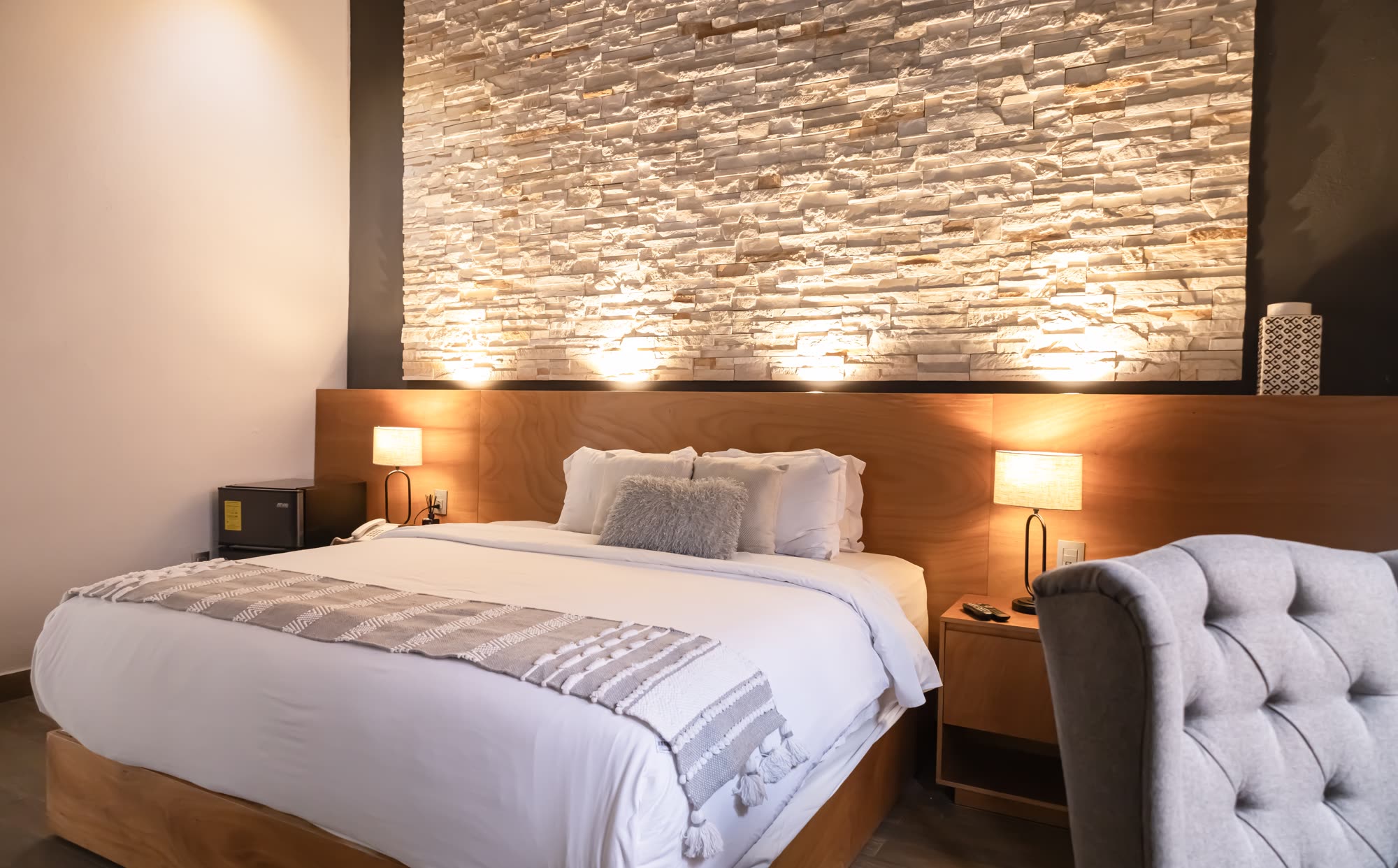 La Jr Suite 217 con su muro de piedra iluminado y sillón