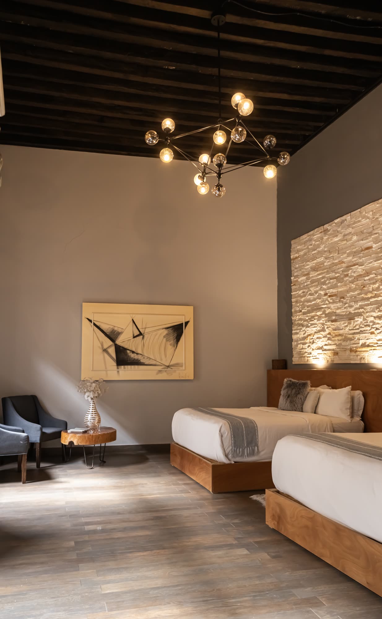 La estancia de la Jr Suite Doble 207 con techo de vigas y candelabro