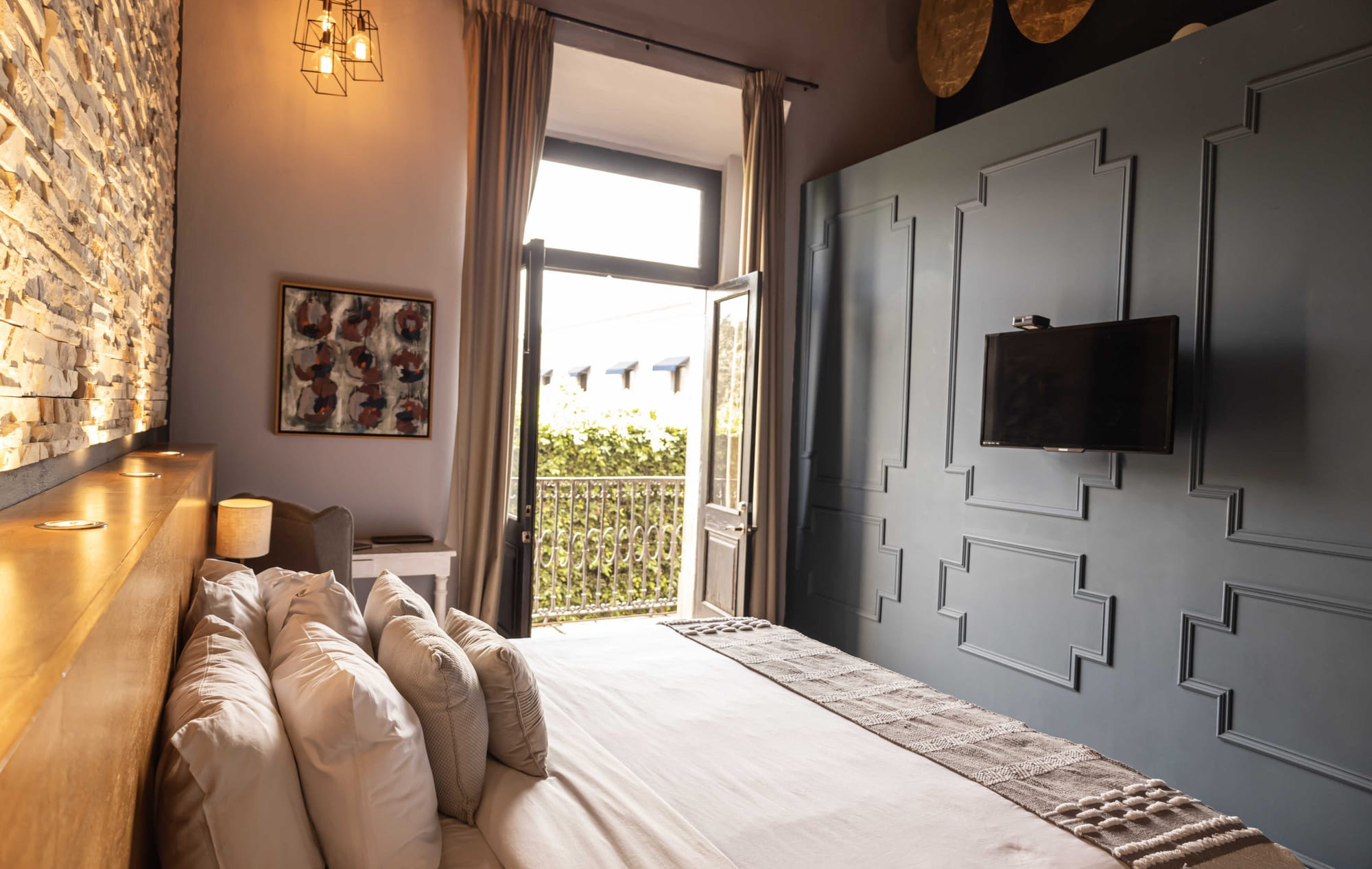 La cama de la Jr Suite Premium 211 junto al balcón abierto