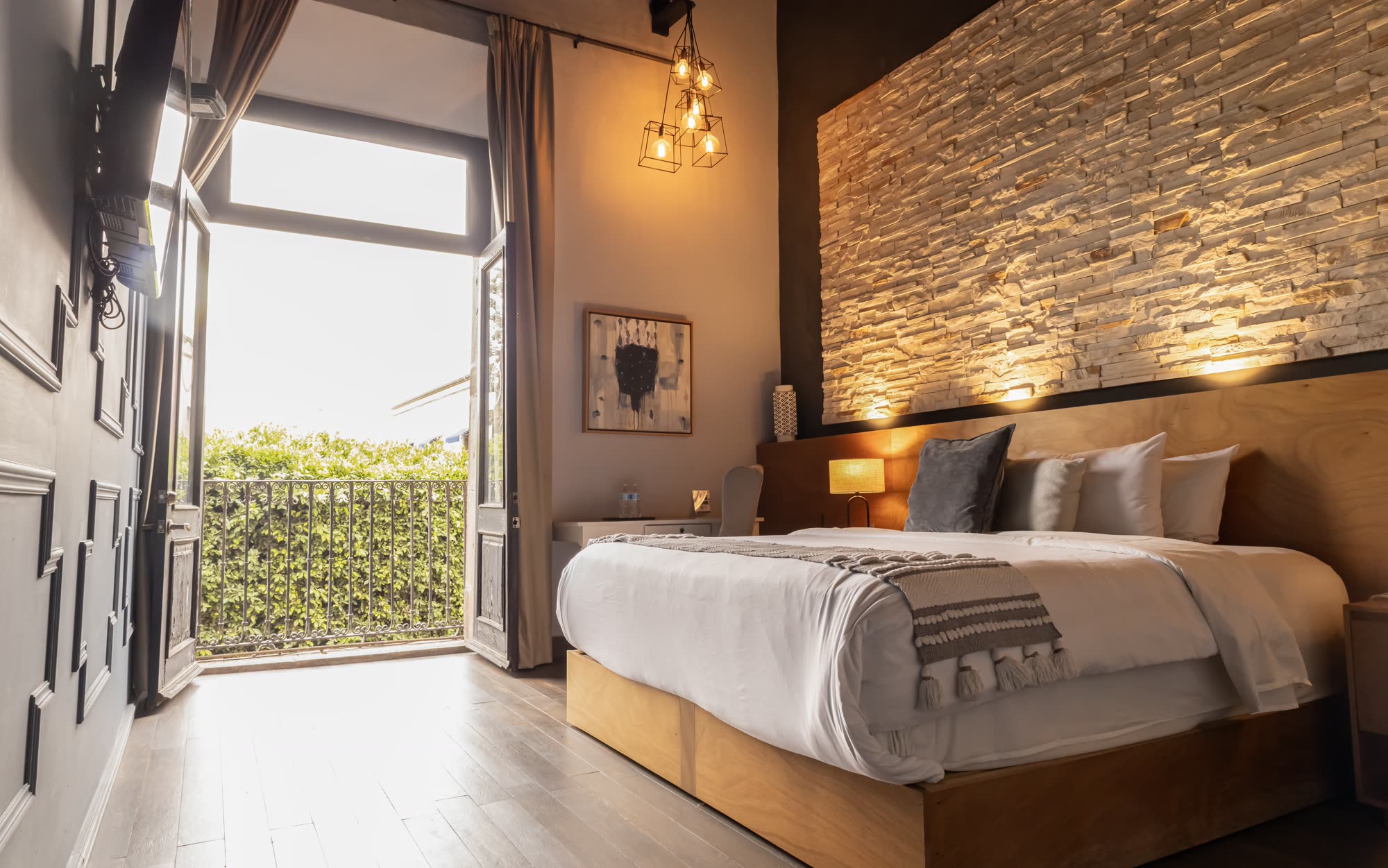La cama de la Jr Suite Premium 212 con el balcón abierto