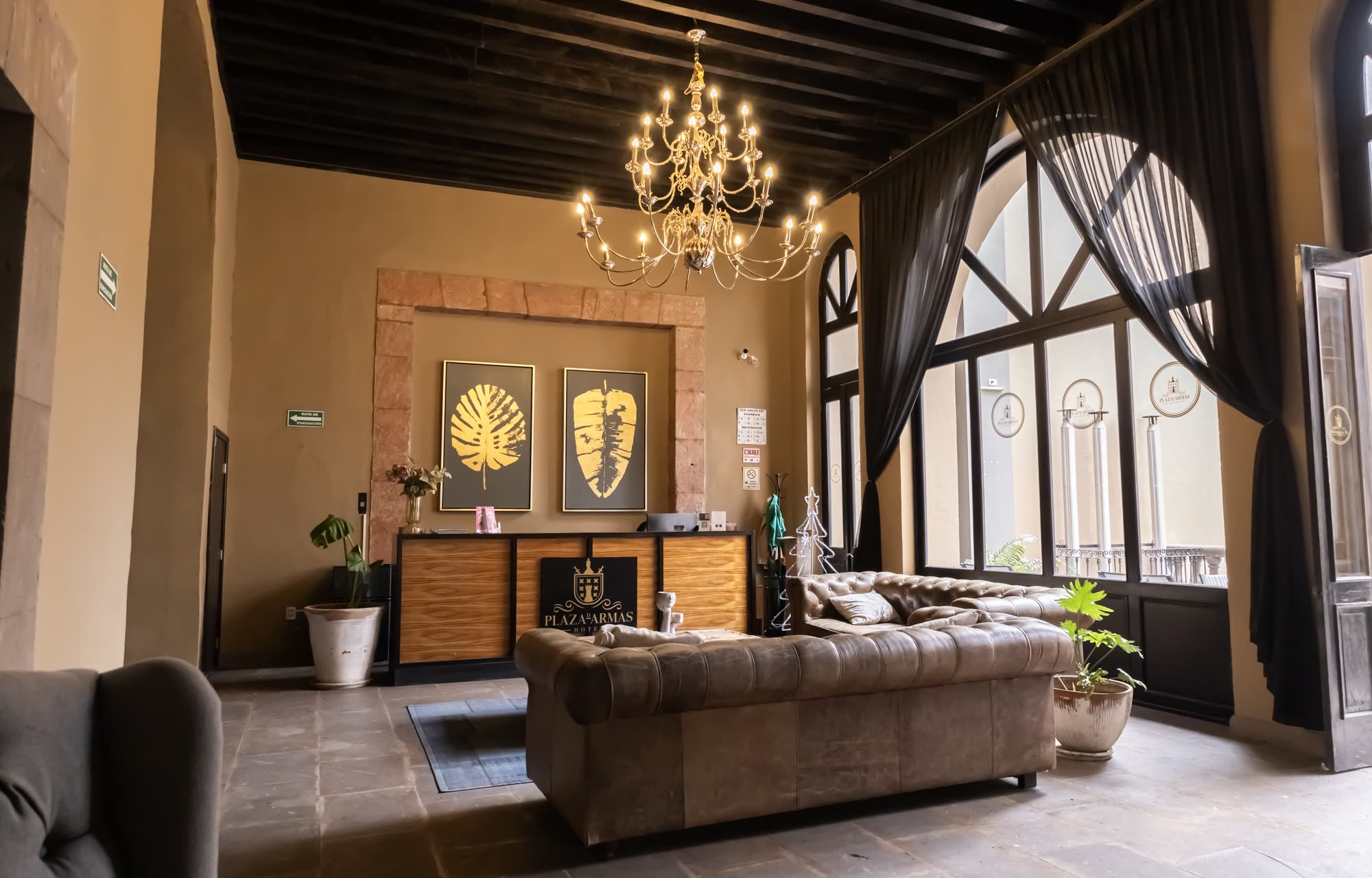 La recepción del hotel bajo el candelabro, con los sillones de piel y el ventanal de arco