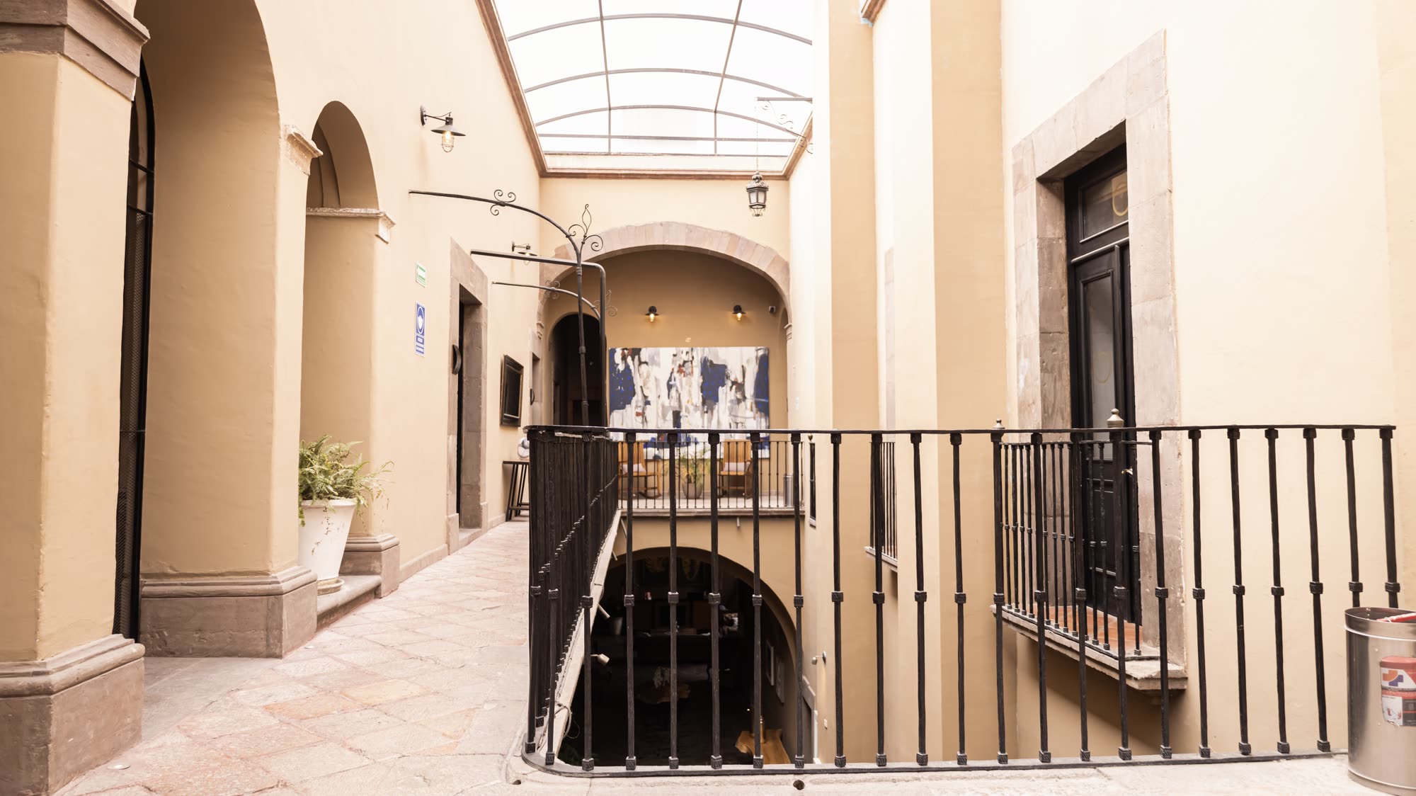 El pasillo del primer nivel con su barandal de herrería, bajo el domo del patio